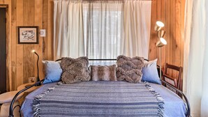 Una habitación con paneles de madera, una cama, una mesita de noche, una lámpara y un cuadro en la pared.