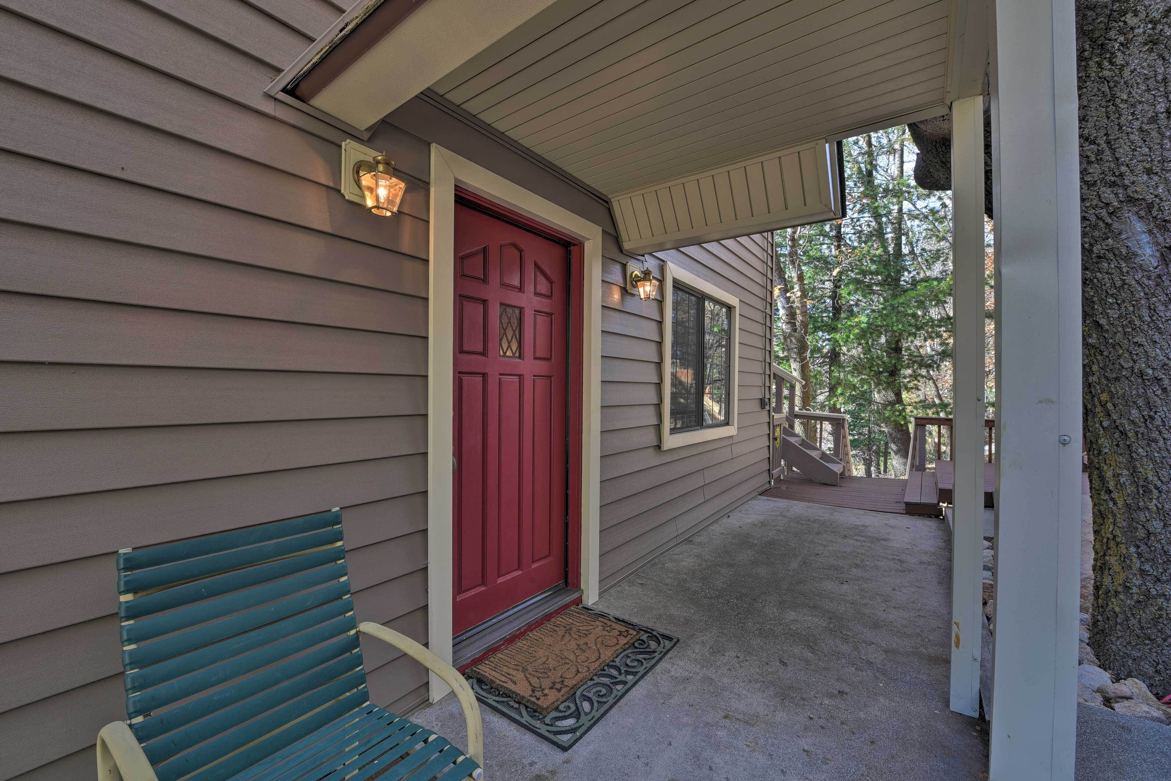 A porch with a red door, a bench, and a small rug.