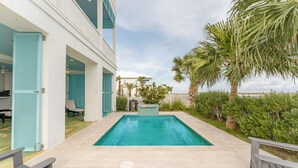 Zona de piscina con vista despejada, una terraza de madera y un edificio con contraventanas azules.