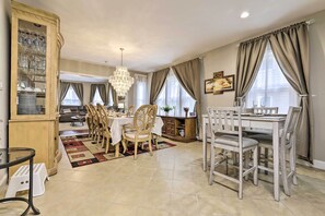 Un comedor con candelabro, mesa, sillas y aparador con cristalería.