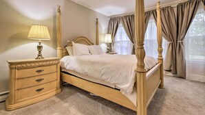Un lit à baldaquin avec une tête de lit en bois, une table de chevet avec une lampe et une commode.