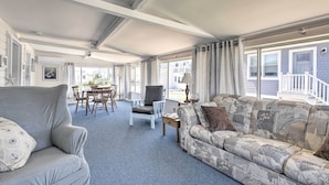A spacious living room with a sofa, armchair, and dining area. - Plum Island Retreat ~ 1-block Walk to Beach! (Newbury)