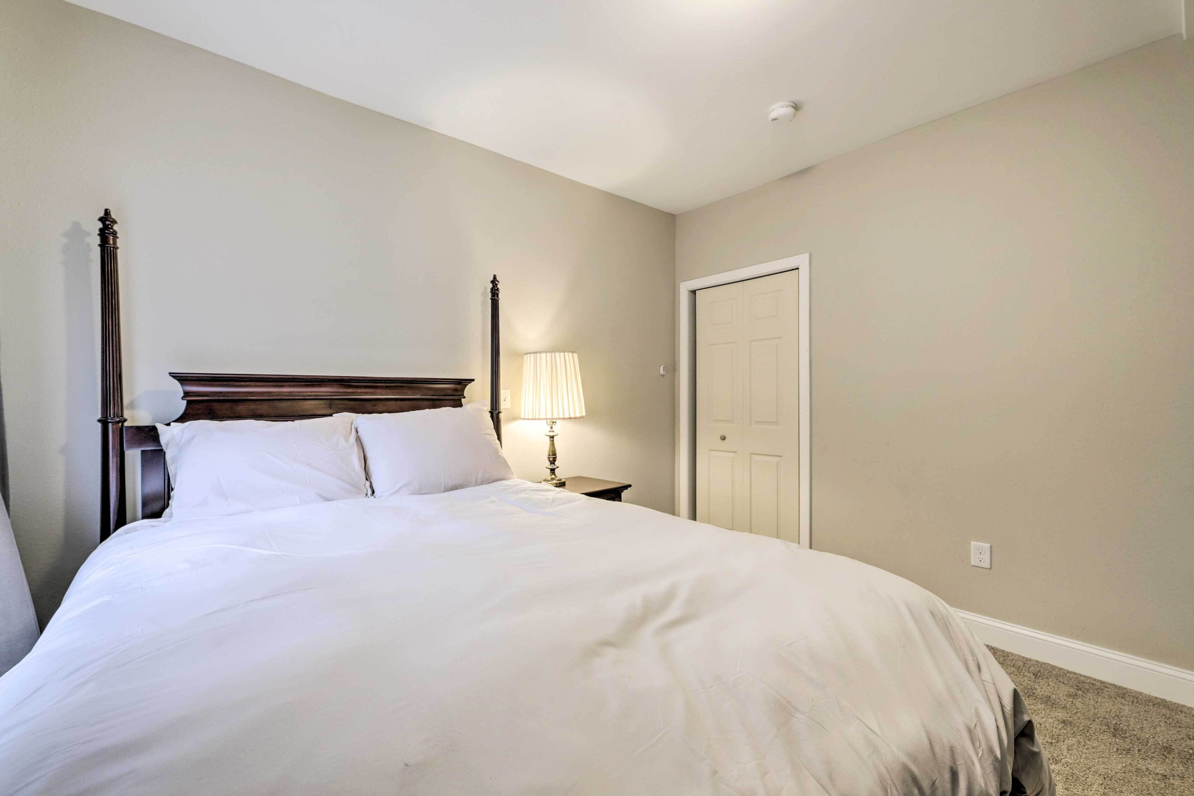 Een net opgemaakt bed met witte lakens in een kamer met beige wanden en een houten hoofdbord.