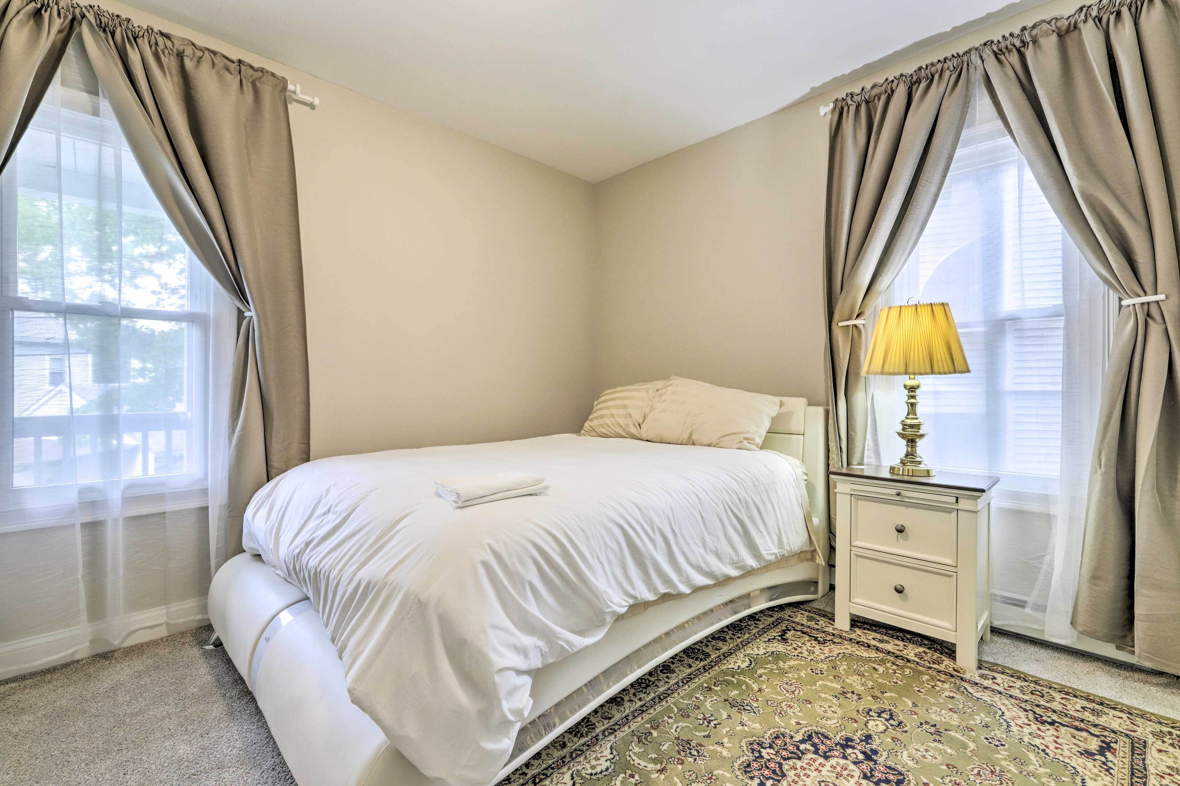 A bedroom with a bed, nightstand, lamp, and a patterned rug.