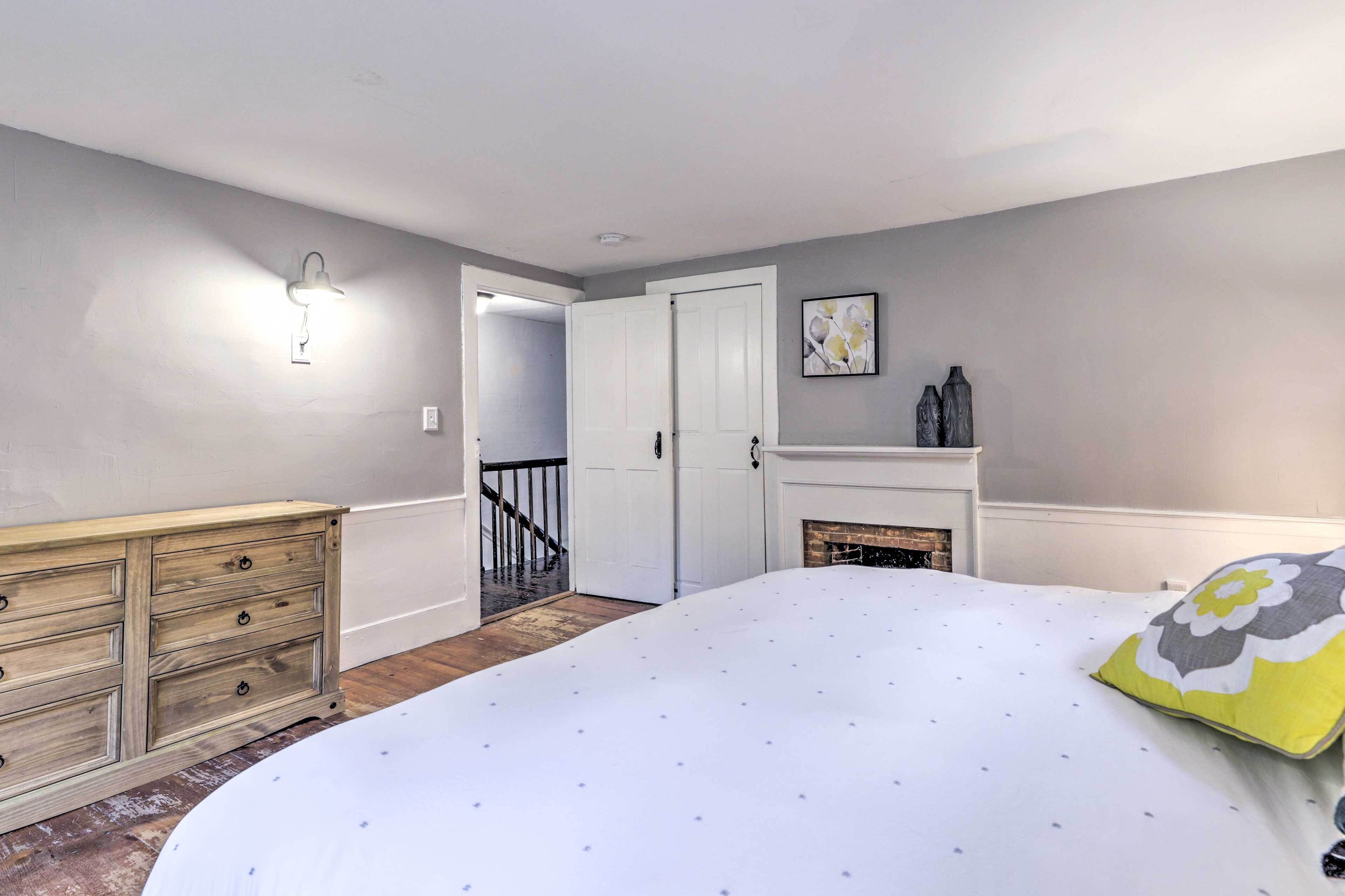 A bedroom with a bed, dresser, and fireplace.