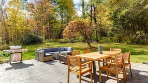 An outdoor patio with a wooden table and chairs, a grill, and a sofa. - Historic Home w/ Modern Updates on < 4 Acres (Royalston)