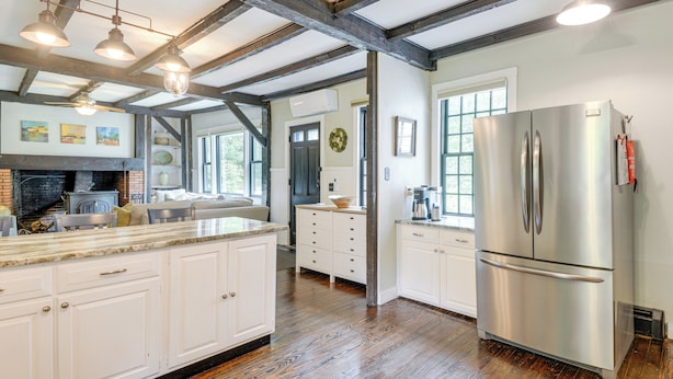 A spacious kitchen with a large island, stainless steel appliances, and exposed wooden beams. - Historic Home w/ Modern Updates on < 4 Acres (Royalston)