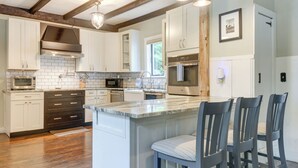 A modern kitchen with white cabinets, a marble island, and bar stools. - Historic Home w/ Modern Updates on < 4 Acres (Royalston)
