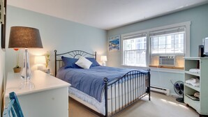 A bedroom with a bed, bedside tables, a lamp, a potted plant, and a window with blinds. - Pool & Beach Access: Coastal Condo in Provincetown (Provincetown)