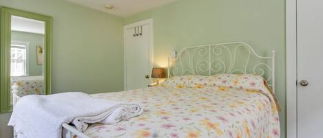 A bedroom with a bed, a nightstand, a lamp, and a door.