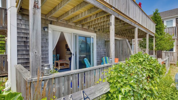 A wooden deck with a covered area, a sliding glass door, and a small table with chairs. - Pool & Beach Access: Coastal Condo in Provincetown (Provincetown)