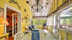 Un coin repas avec une table dressée pour deux personnes, un vase bleu servant de centre de table et une vue sur l’extérieur grâce à de grandes fenêtres.