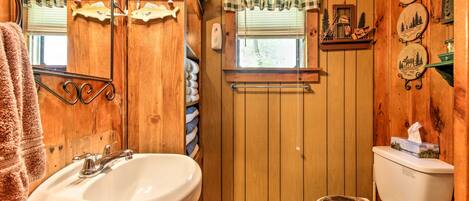 A wooden bathroom with a sink, toilet, and towel rack.