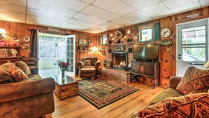 Une chambre confortable, aménagée dans le style d’un chalet, avec une cheminée, des murs en bois, une télévision et un coin salon confortable.
