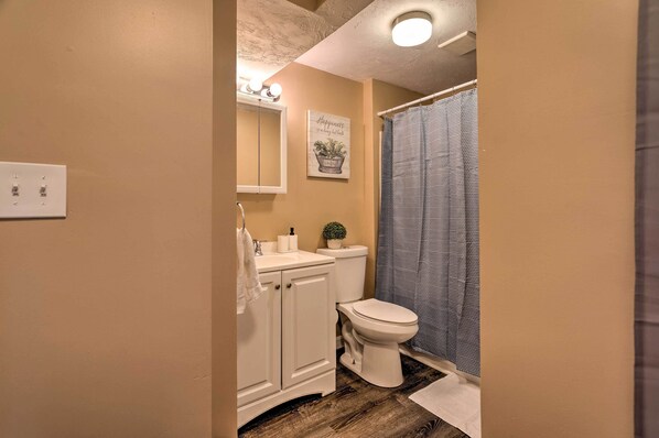 A bathroom with a toilet, sink, cabinet, and a shower curtain.