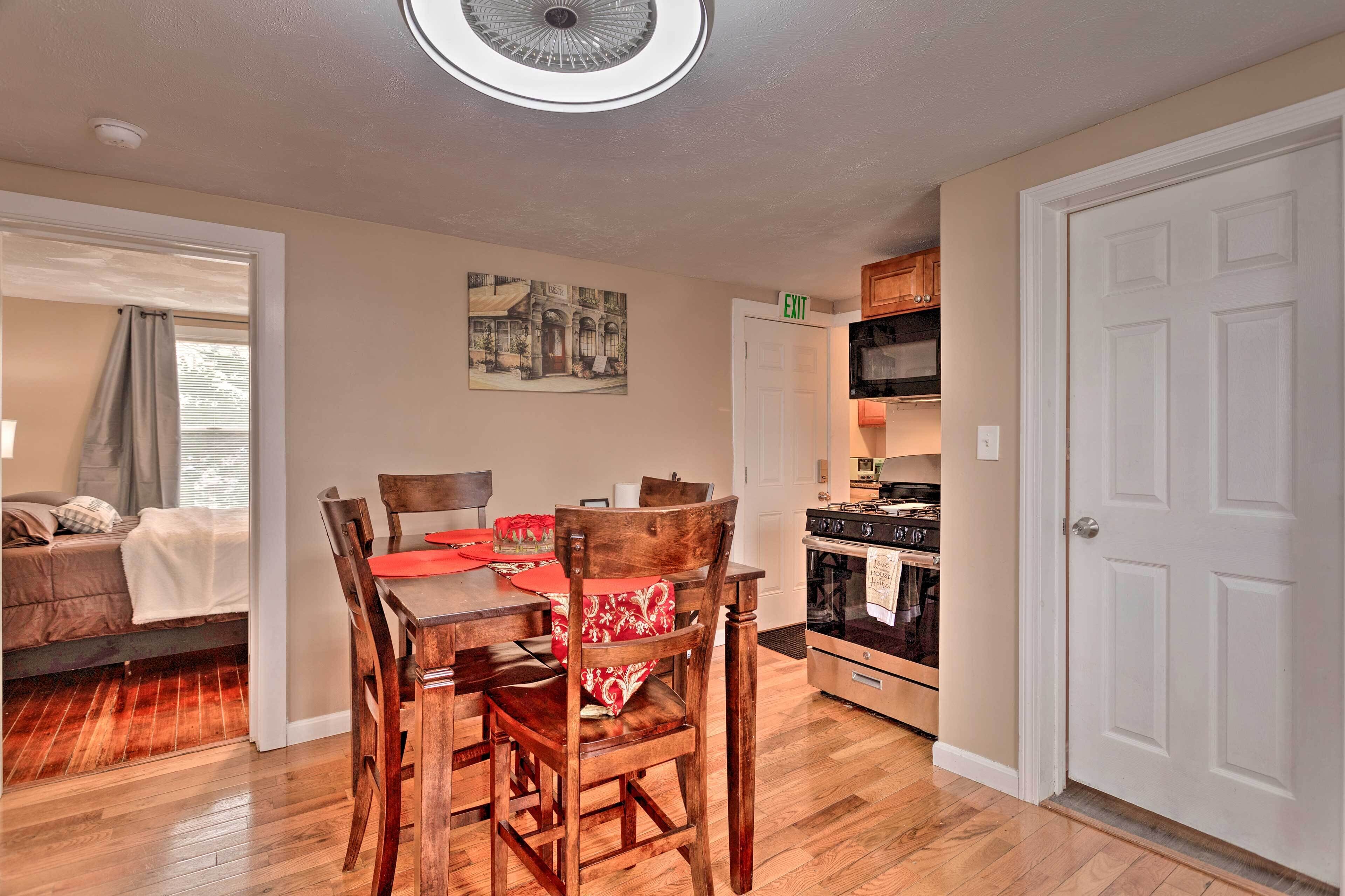 A dining area with a wooden table and chairs, a kitchen with an oven and cabinets, and a door marked "EXIT".