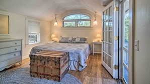 Ein Schlafzimmer mit einem großen Bett, einem alten Koffer, einem Schminktisch und einem Fenster mit Blick.