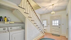 A laundry room with two white washers and dryers, a wooden staircase, and a green rug on the floor. - Apt on Vineyard Haven Near Nantucket Sound! (Vineyard Haven)