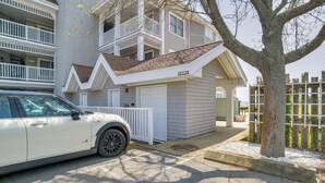 Ein zweistöckiges Gebäude mit weißer Fassade, einer Garage und einem Baum davor.