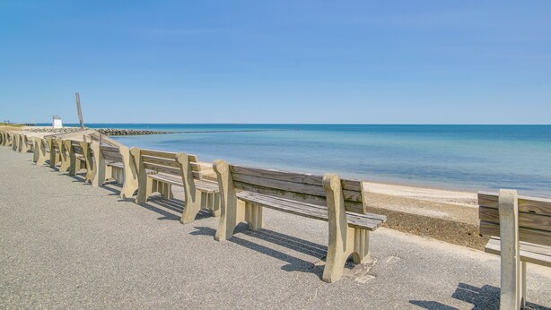 Ein Strand mit Holzbanken und freiem Blick auf das Meer.