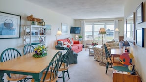 Ein geräumiges Wohnzimmer mit Essbereich, einer Couch, einem Fernseher und Blick ins Freie.