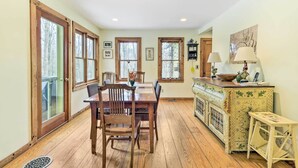 Un coin repas avec une table et des chaises en bois, un buffet orné de carreaux décoratifs et une porte donnant sur un balcon.