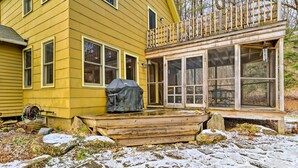 Une maison jaune avec un porche et une terrasse en bois.