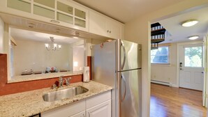 A kitchen with a stainless steel refrigerator, a granite countertop, and white cabinetry. - Shop, Dine, Explore Commercial St! Coastal Retreat (Provincetown)