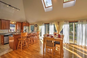 A spacious kitchen with wooden cabinets, a central island, and a dining area with a table and chairs. - Families Welcome! East Falmouth Home 4 Mi to Beach (East Falmouth)