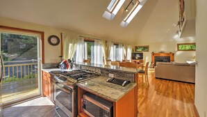 A modern kitchen with a gas stove, oven, and microwave. There is a dining area with a sofa and a fireplace.