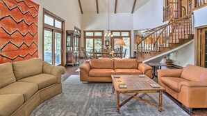 A spacious living area with a large sofa, a coffee table, and a staircase leading to an upper level. - Ornate Lake Arrowhead Home With Deck (Lake Arrowhead)