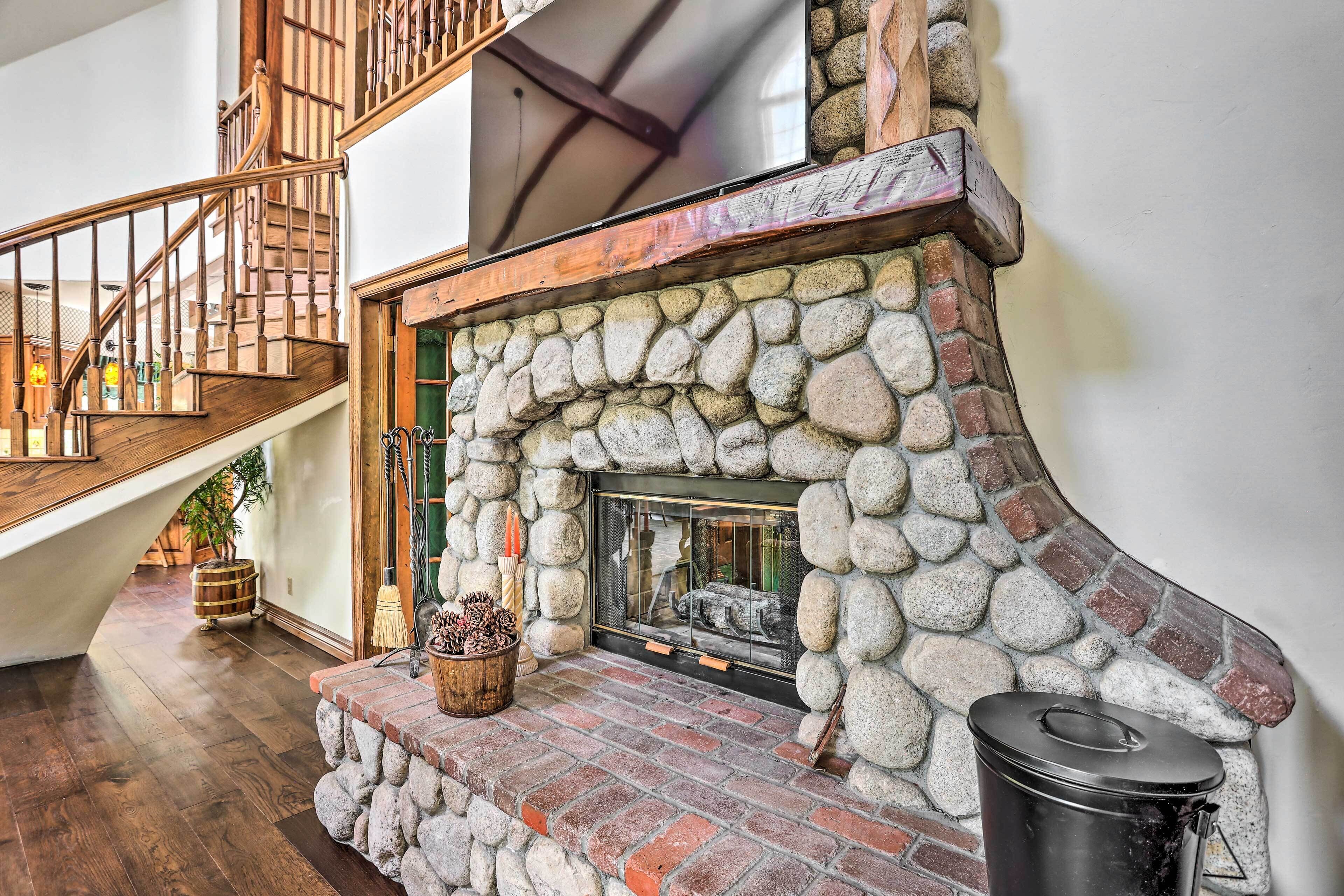 Une cheminée en pierre avec un manteau en briques, un escalier en bois et une décoration rustique.