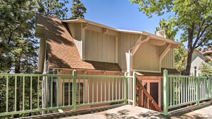 A two-story house with a green metal fence, a covered porch, and a staircase leading to the upper floor.