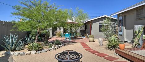 A backyard with a fire pit, patio furniture, and various plants.