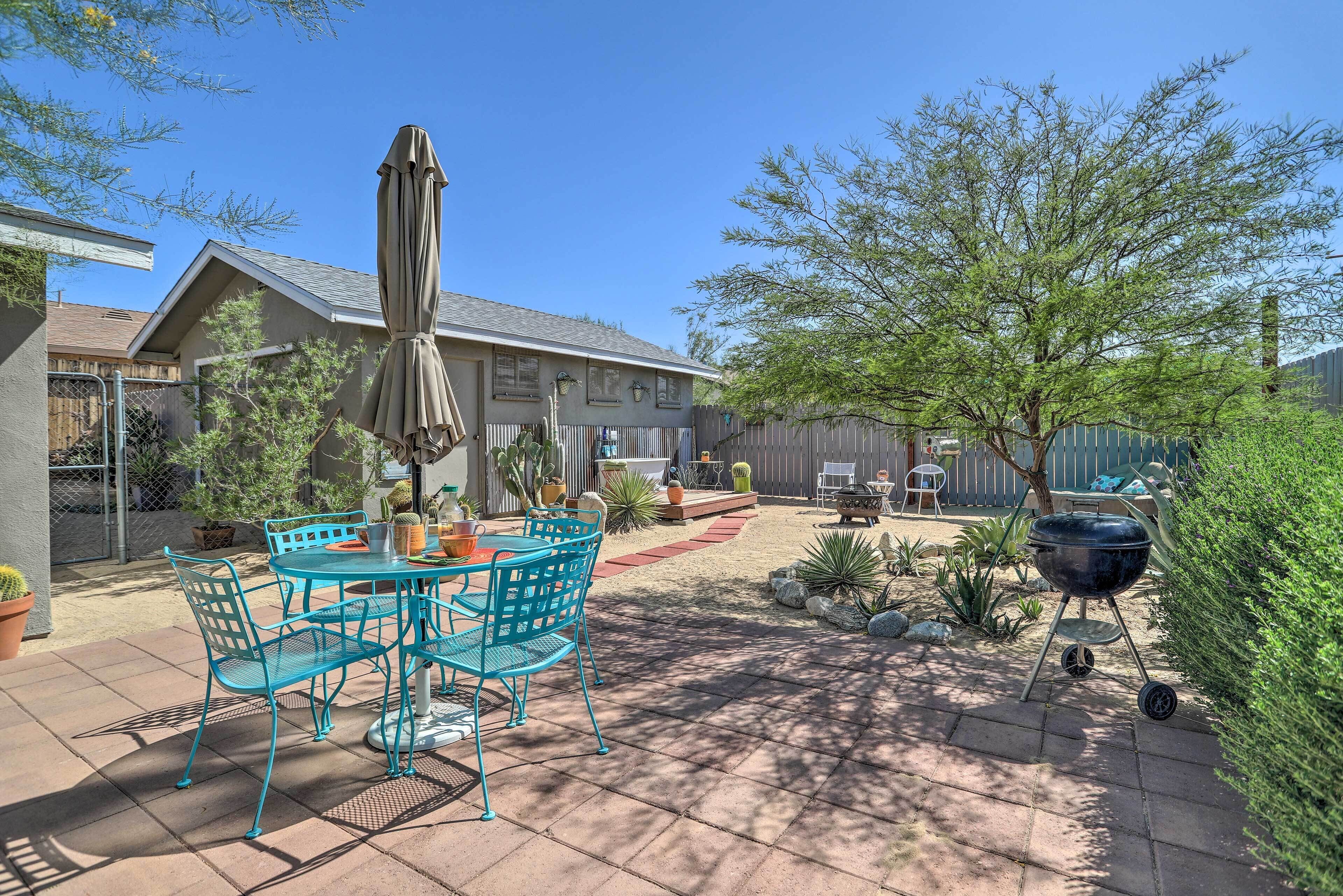 A patio with a table and chairs, a barbecue grill, and various potted plants.