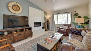 Ein Wohnzimmer mit Fernseher, Ledersofa, Couchtisch und Kamin.