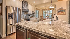 A kitchen with a stainless steel refrigerator, a marble countertop, and a chandelier. - Near Bear Mountain & Big Bear Lake: Gem w/ Hot Tub (Big Bear City)