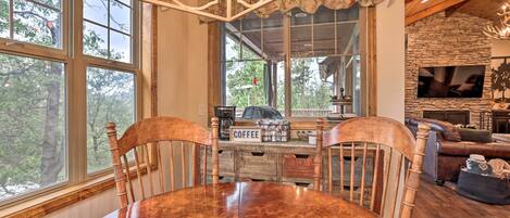 Un comedor con mesa y sillas de madera, una estación de café y una chimenea de piedra.