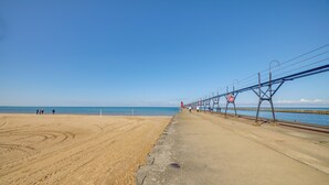 A beach with a concrete walkway and a pier extending into the water.