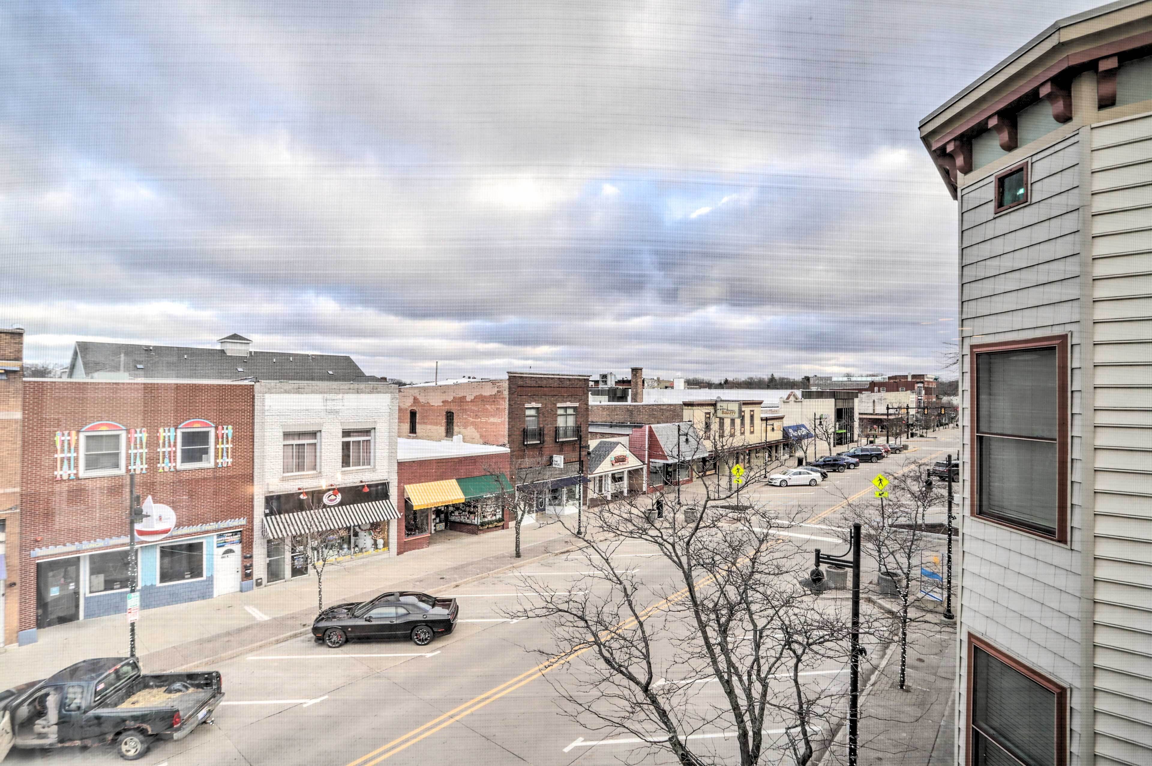 A street view with buildings, a road, and a parked car.