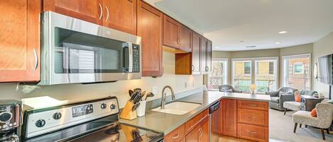 Una cocina moderna con electrodomésticos de acero inoxidable, armarios de madera y un amplio ventanal que proporciona luz natural.