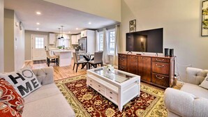 A modern living room with a sofa, a glass coffee table, a wooden cabinet, and a flat-screen TV. - Worcester Vacation Rental w/ Ideal Location! (Worcester)