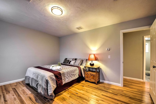 Un dormitorio con una cama, una mesita de noche, una lámpara y una luz en el techo.