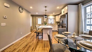 A modern kitchen with a central island, dining area with glass table, and a view of the city through large windows. - Worcester Vacation Rental w/ Ideal Location! (Worcester)