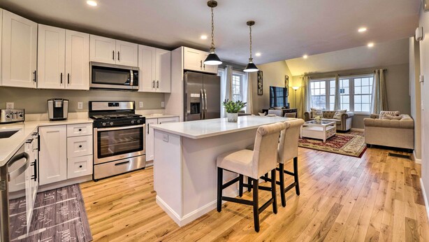 A modern kitchen with white cabinets, stainless steel appliances, and a central island with bar stools. - Worcester Vacation Rental w/ Ideal Location! (Worcester)