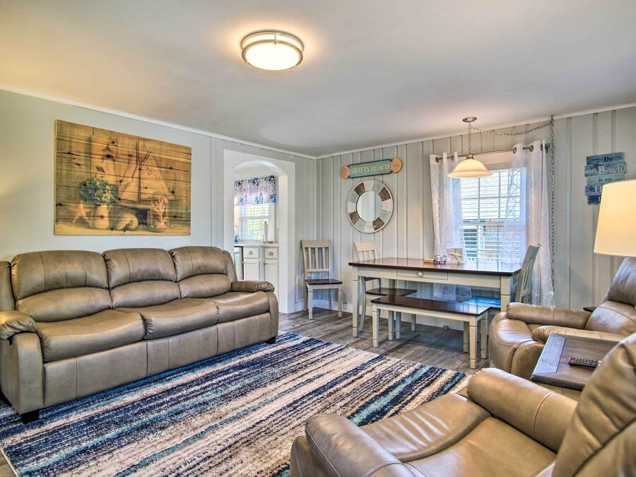 A living room with a beige leather sofa, a dining table, and a striped rug.