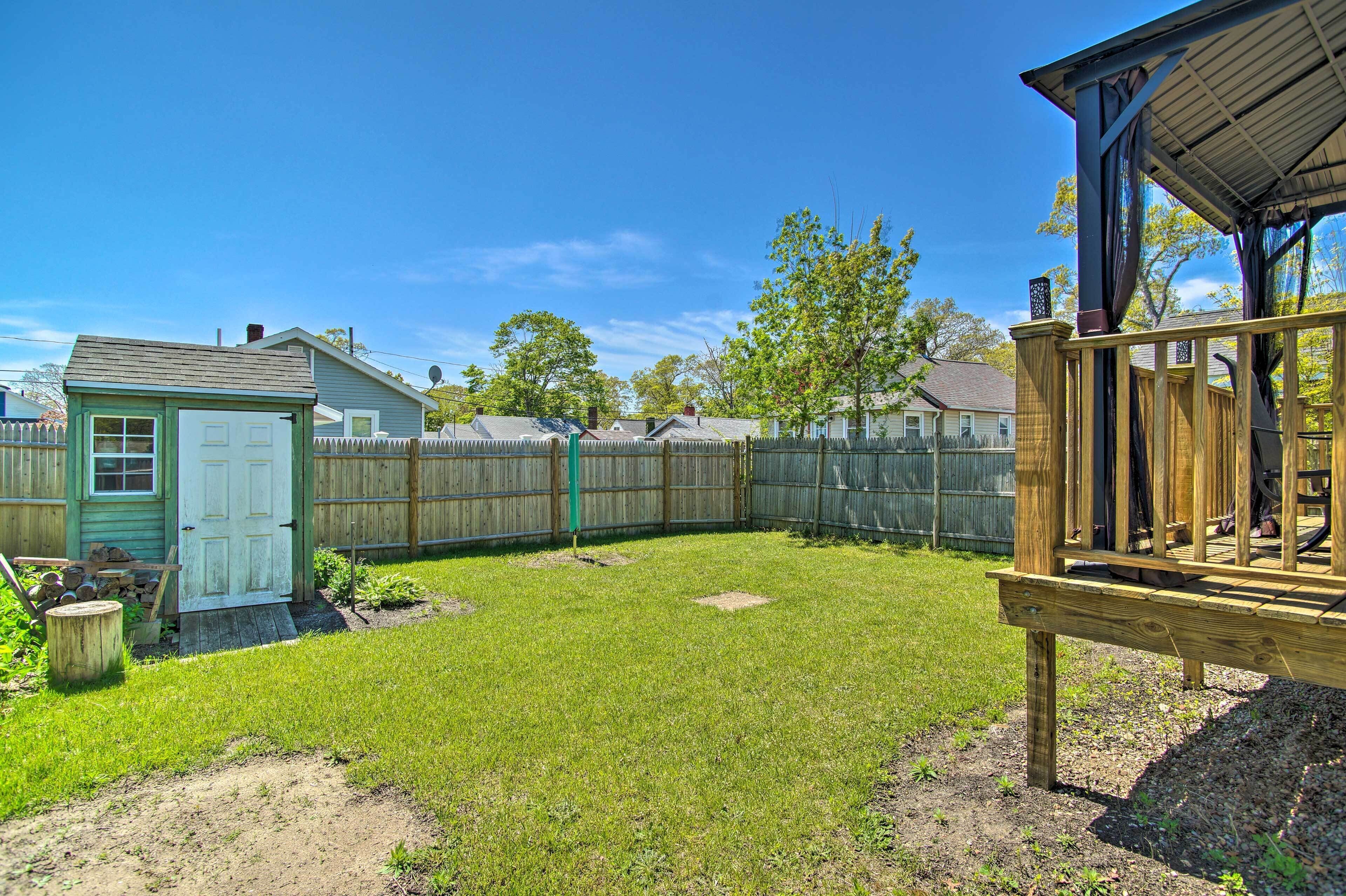 A backyard with a wooden deck, a shed, and a fenced area.