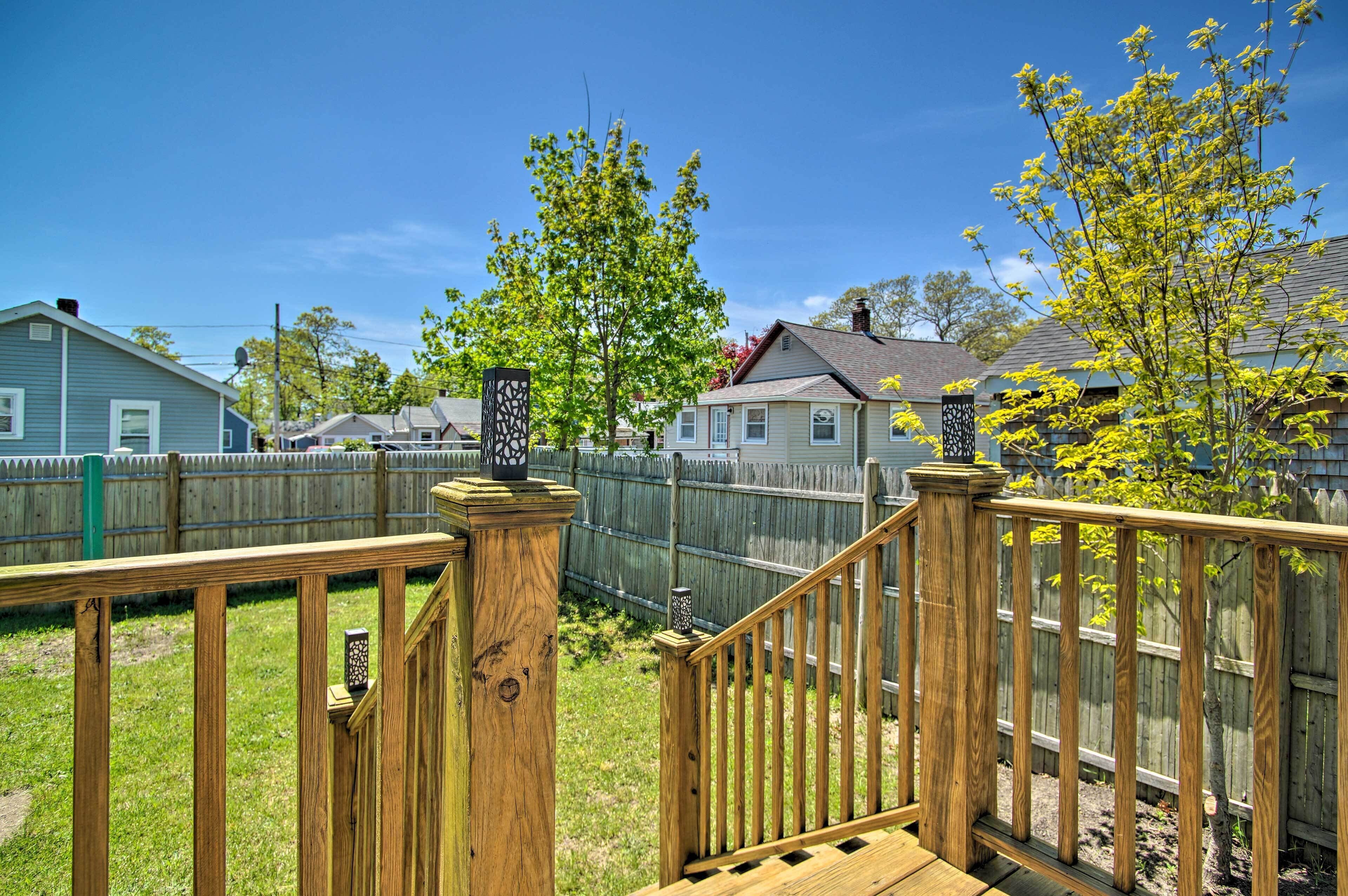 A wooden deck with a railing, a wooden fence, and houses in the background.