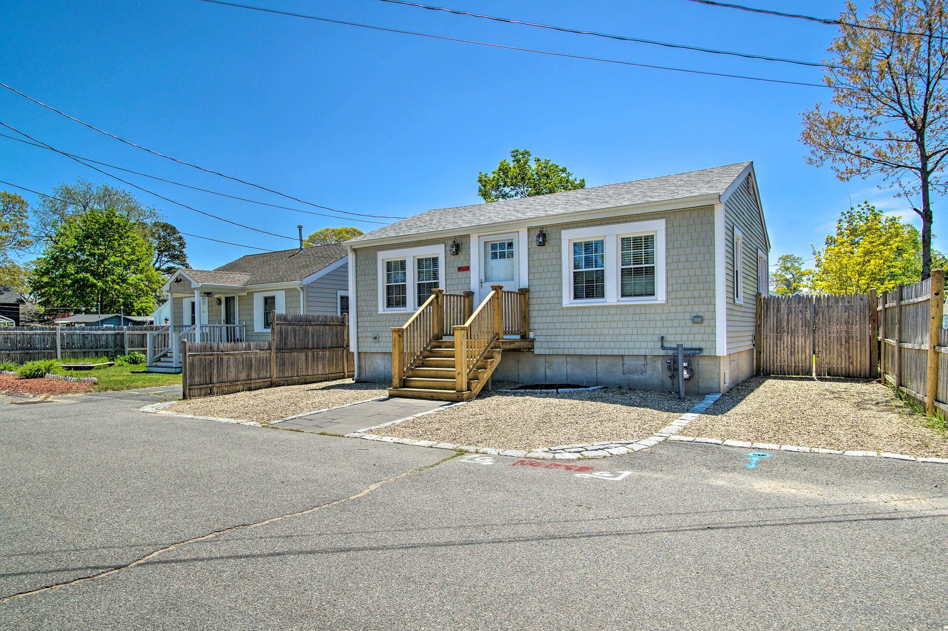 A single-story house with a front porch, a wooden staircase, and a fenced yard.