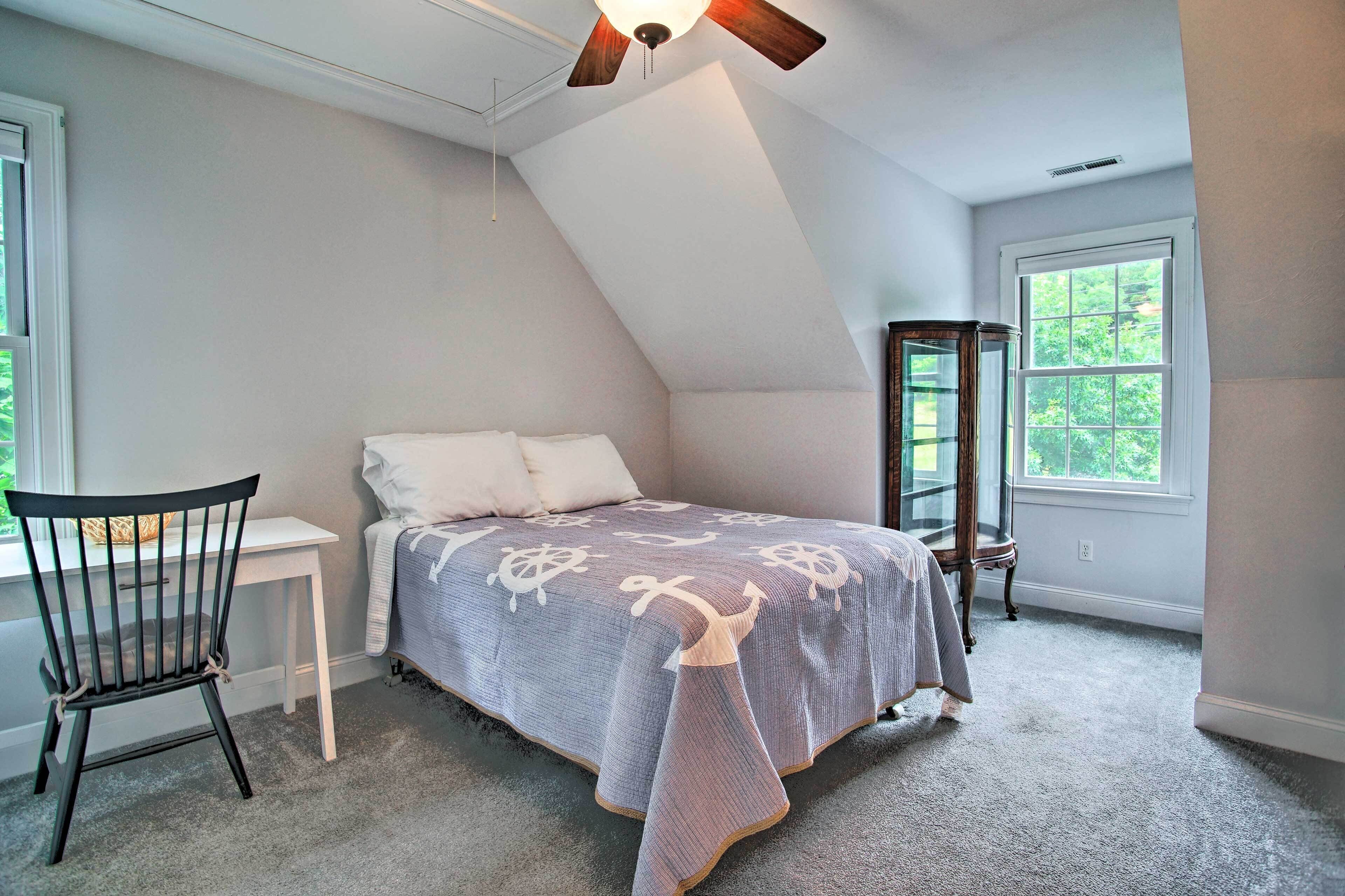 Un dormitorio con cama, escritorio, silla y ventana.